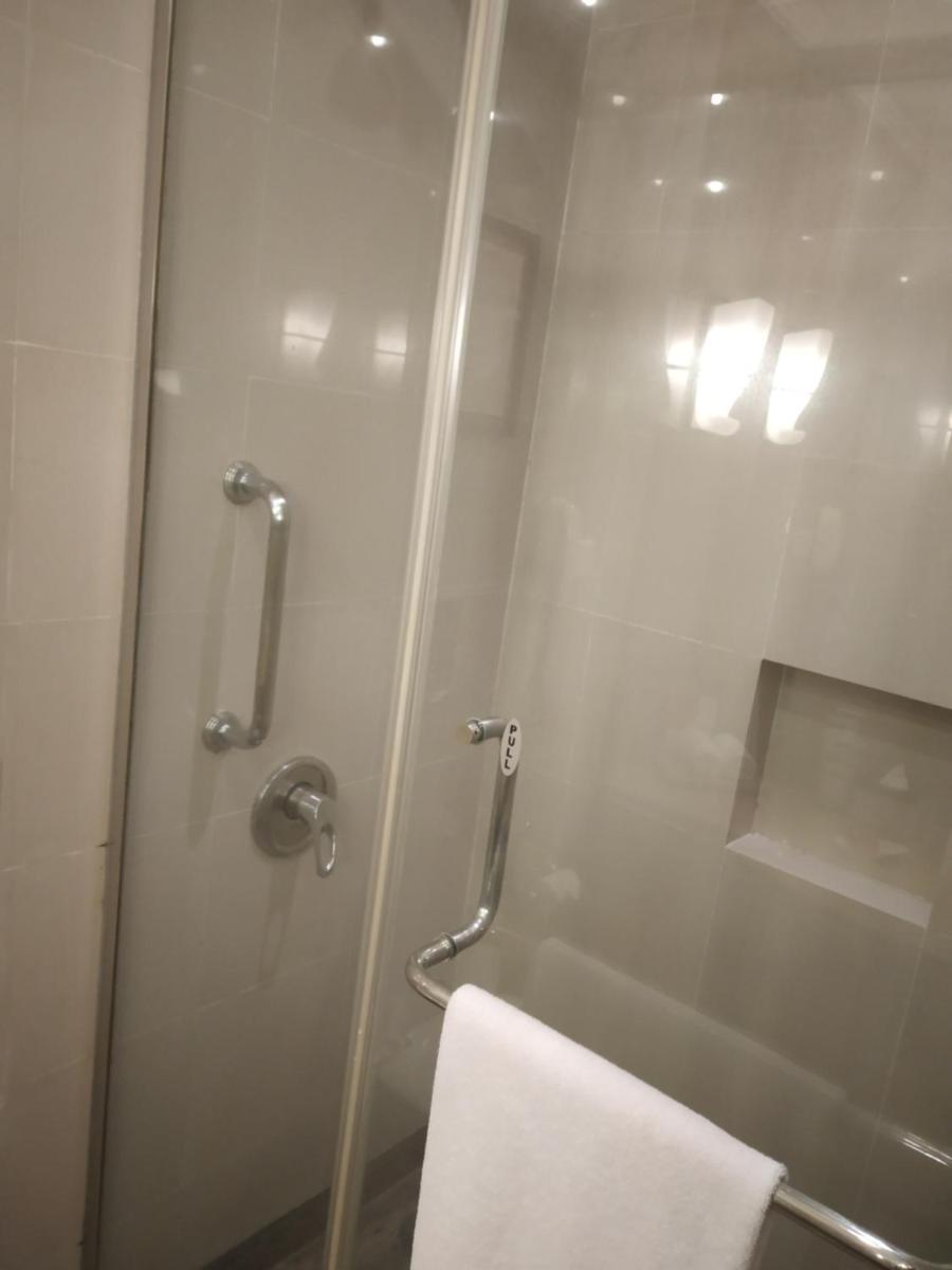 a shower with a glass door and a towel at The Lalit Ashok in Bengaluru a shower with a glass door and a towel at The Lalit Ashok in Bengaluru
