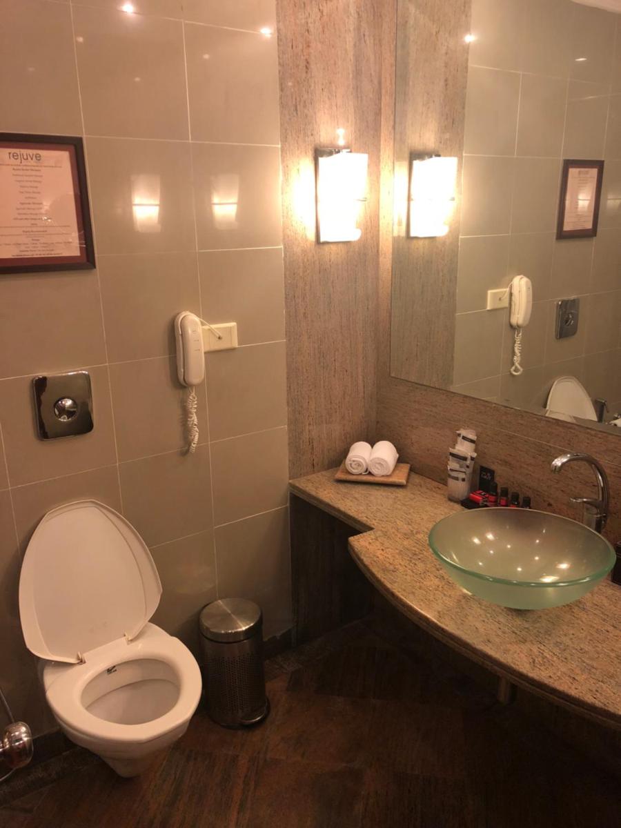 a bathroom with a toilet and a sink and a phone at The Lalit Ashok in Bengaluru a bathroom with a toilet and a sink and a phone at The Lalit Ashok in Bengaluru