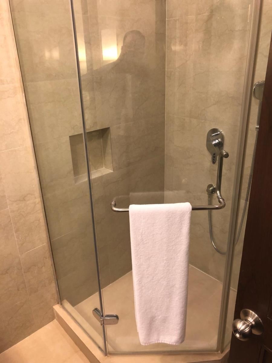 a shower with a white towel in a bathroom at The Lalit Ashok in Bengaluru a shower with a white towel in a bathroom at The Lalit Ashok in Bengaluru