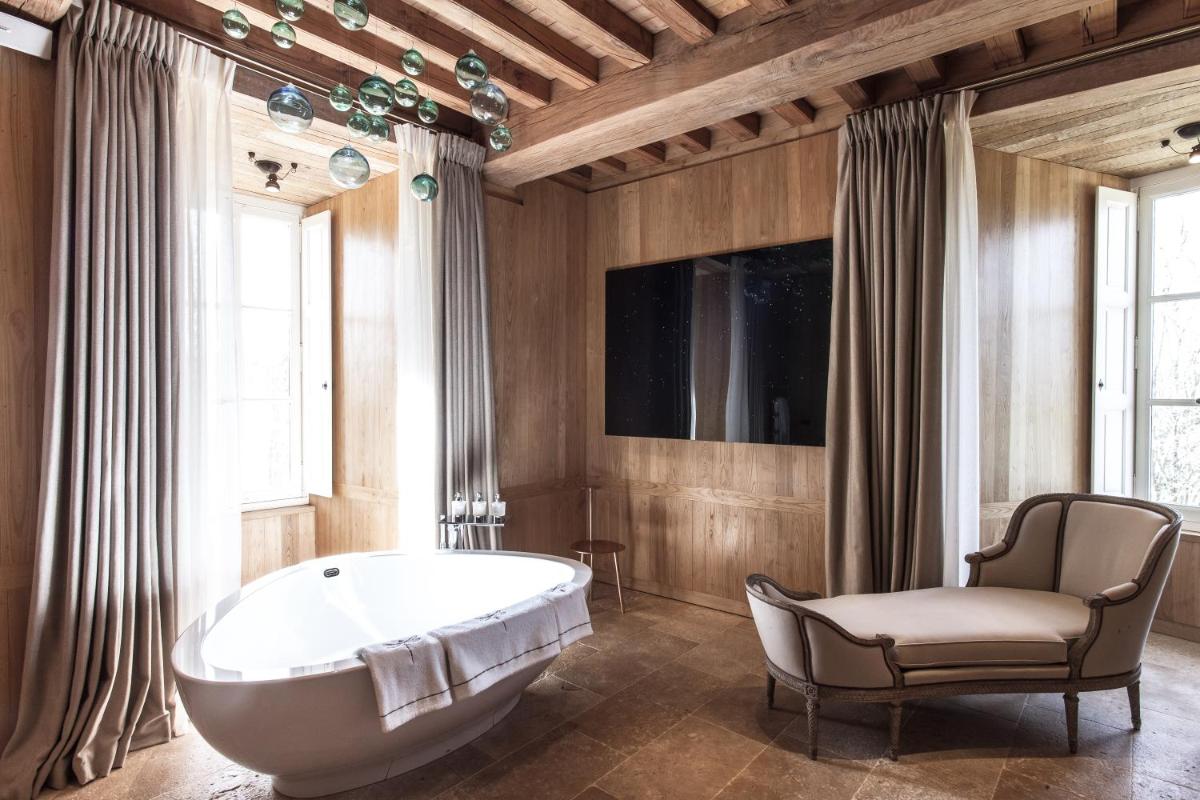 une grande salle de bains avec baignoire et chaise dans l'établissement Domaine des Etangs, Auberge Collection, à Massignac