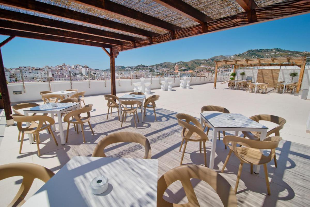 Un patio con mesas y sillas en un tejado. en Bahía Almuñecar, en Almuñécar