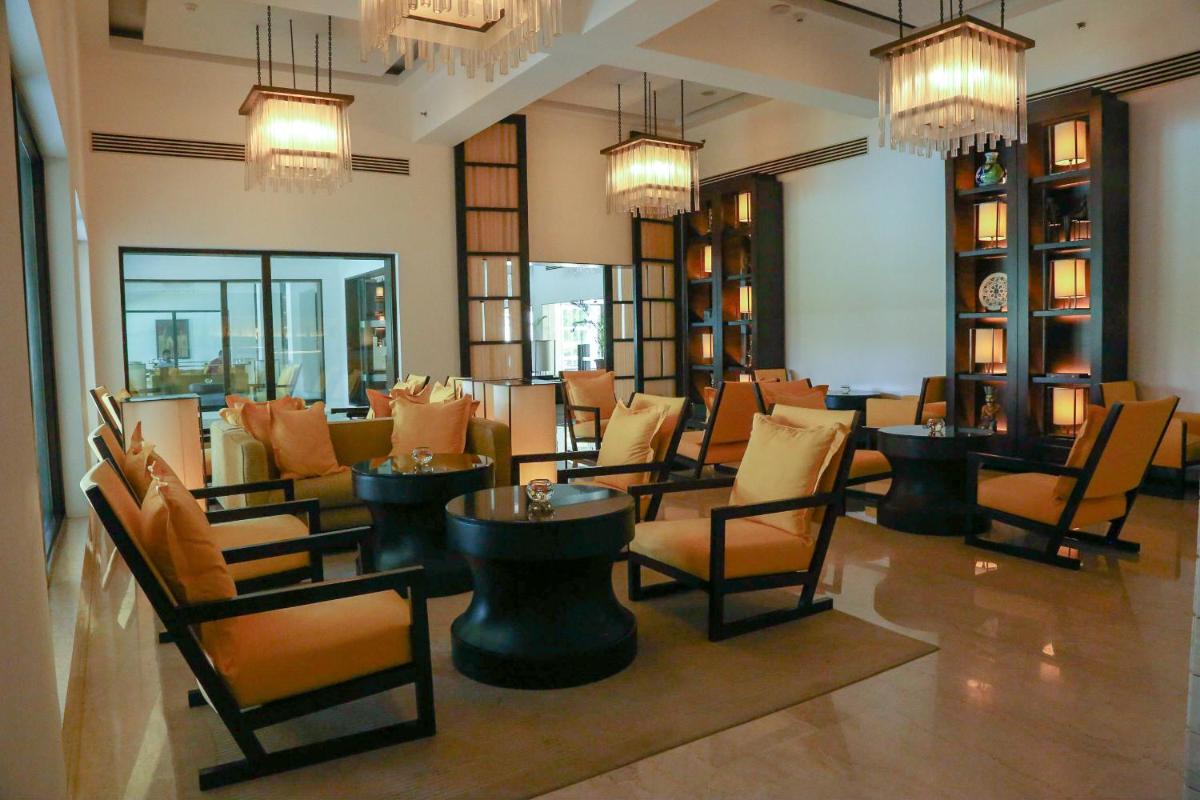 a restaurant with chairs and tables and chandeliers at Trident Agra in Agra