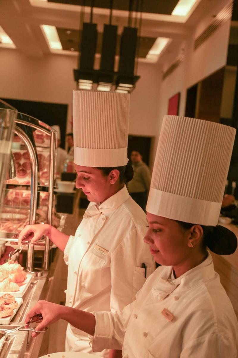 two chefs standing in a kitchen preparing food at Trident Agra in Agra