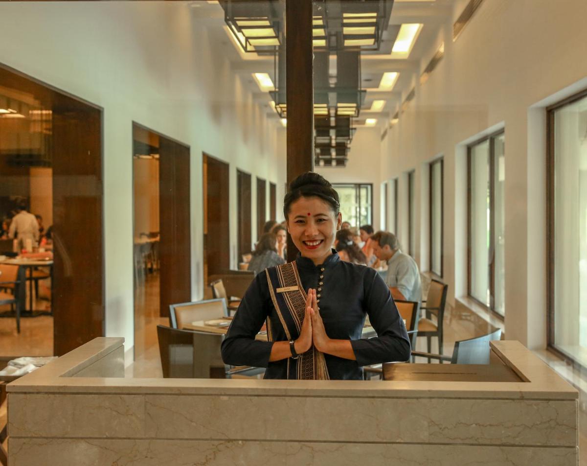 a woman is standing in a restaurant with her hands in front at Trident Agra in Agra