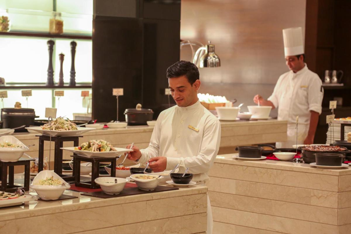 a chef preparing food in a restaurant kitchen at Trident Agra in Agra