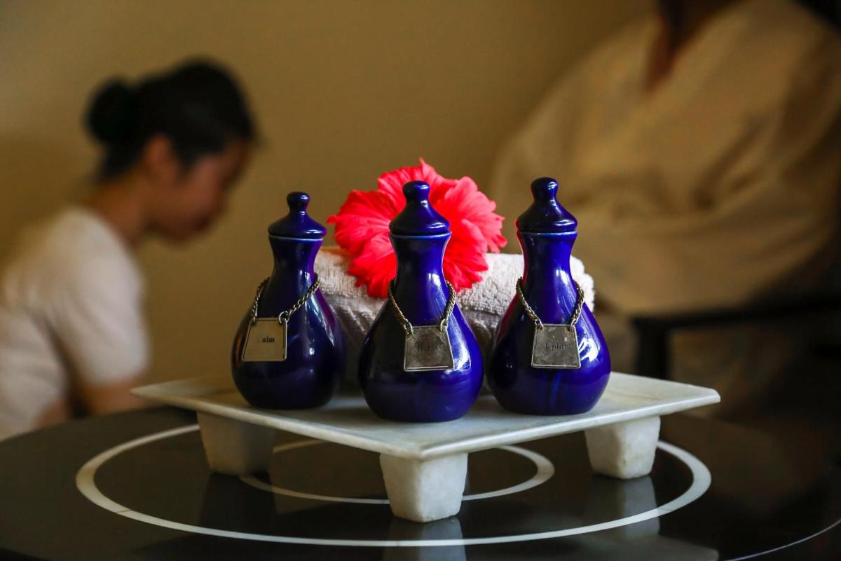four blue vases on a table with a red flower at Trident Agra in Agra