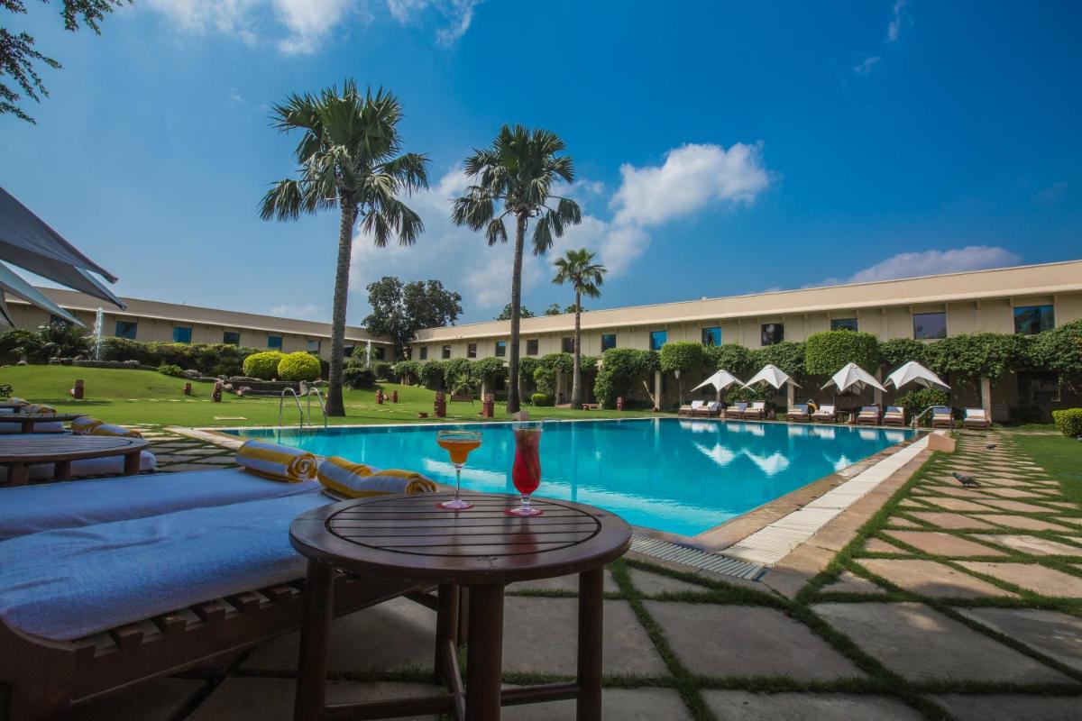 a pool at a resort with a table and chairs at Trident Agra in Agra