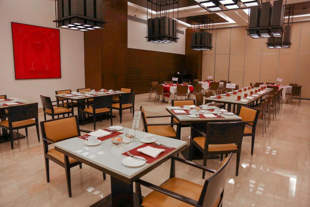 a dining room with tables and chairs and a red painting at Trident Agra in Agra