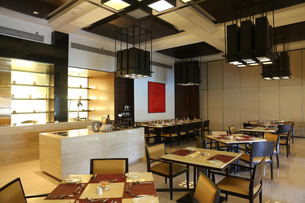 a restaurant with tables and chairs and a bar at Trident Agra in Agra