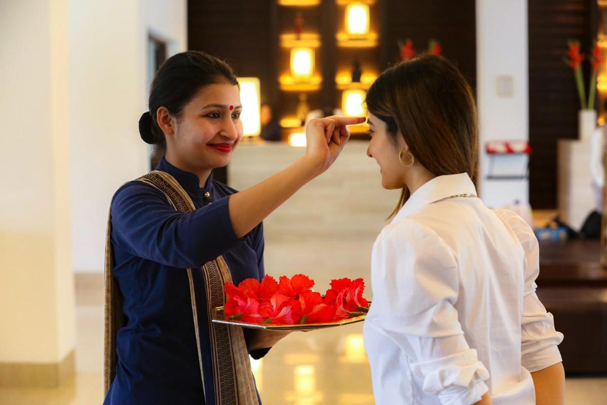 a woman is holding a tray of red flowers at Trident Agra in Agra