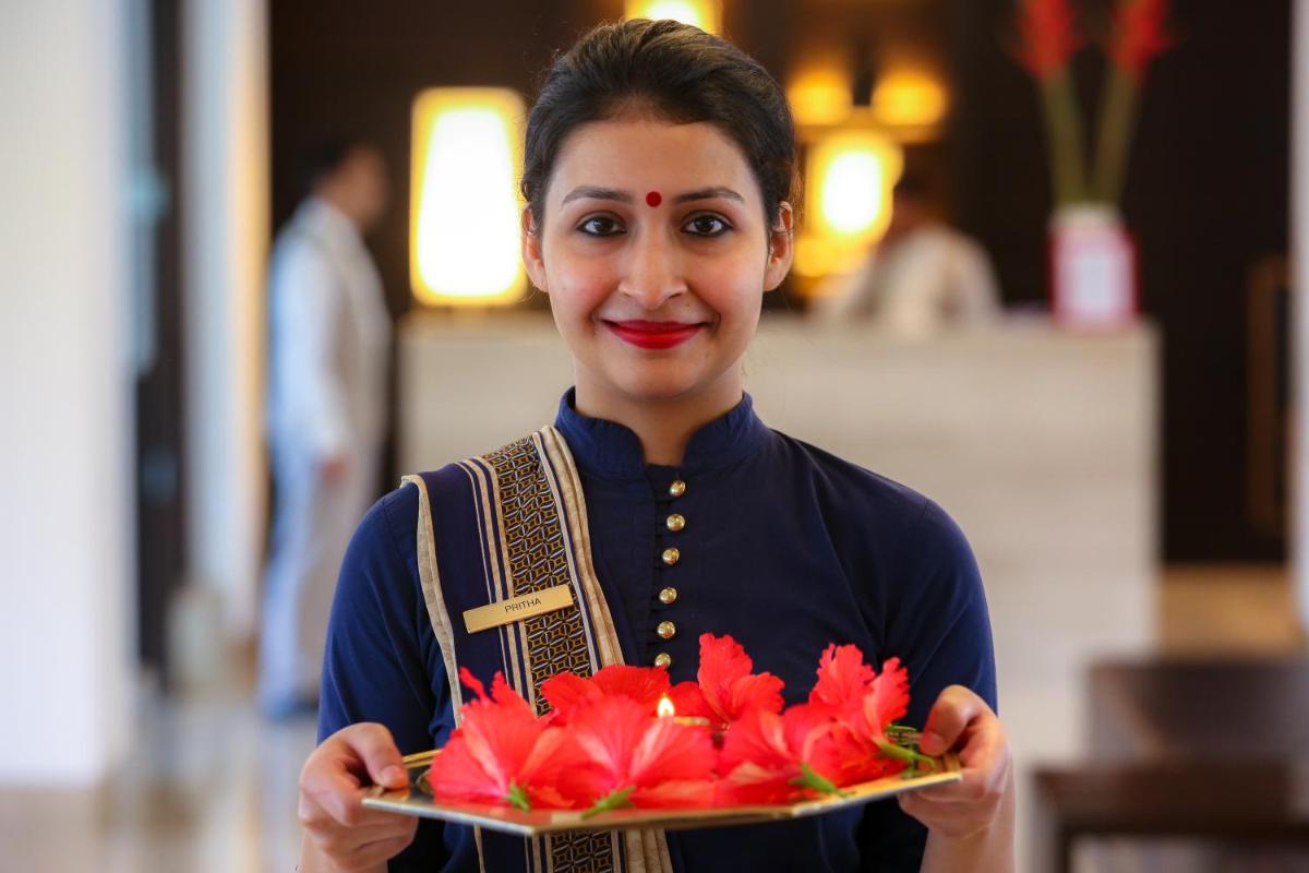 a woman holding a plate with flowers on it at Trident Agra in Agra
