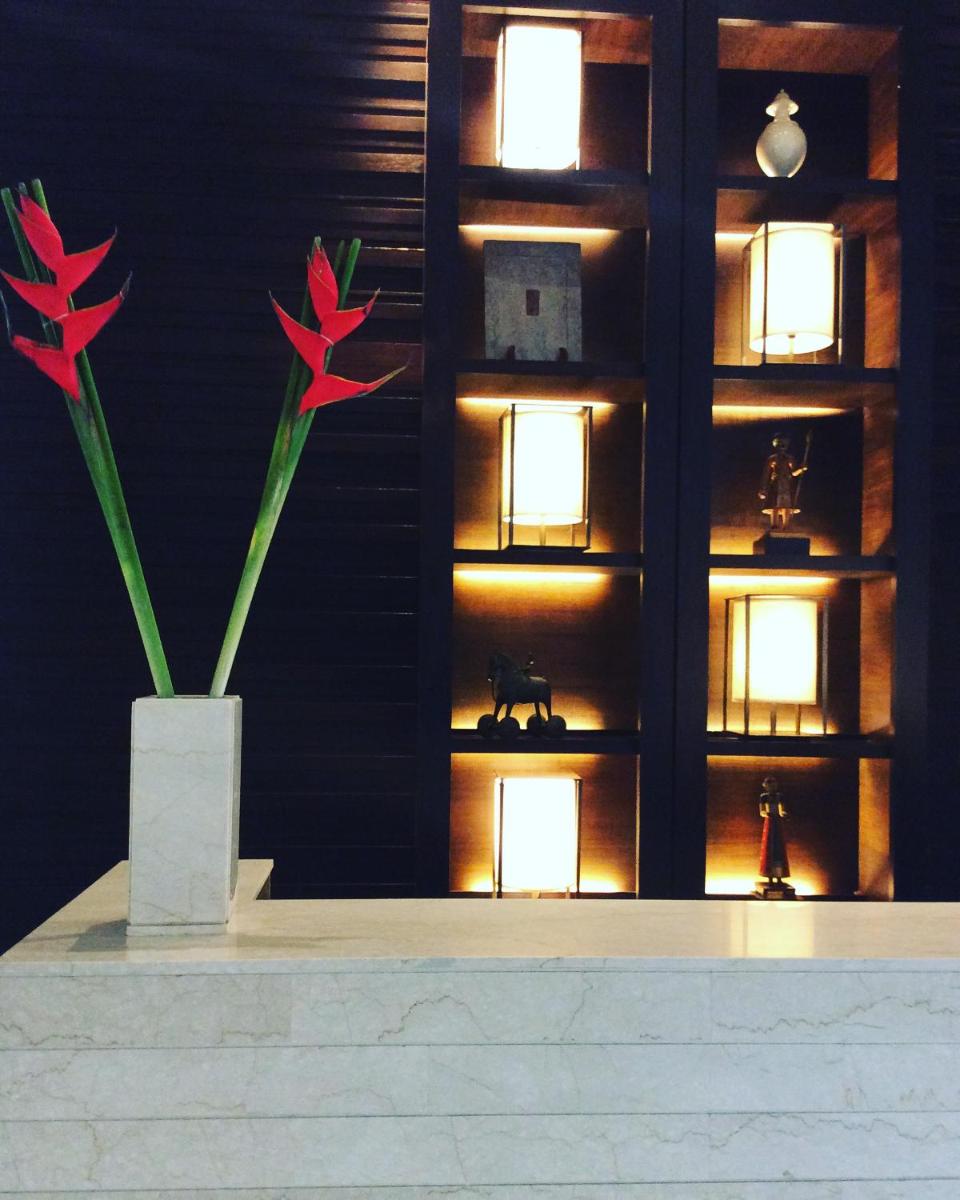 a vase with red flowers in front of a wall at Trident Agra in Agra