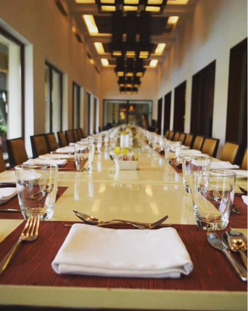 a long table with white napkins and glasses on it at Trident Agra in Agra