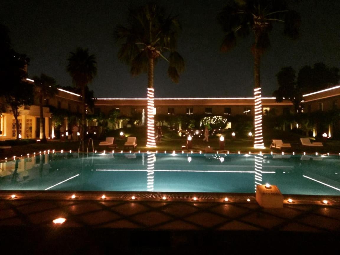 a swimming pool at night with palm trees and a building at Trident Agra in Agra