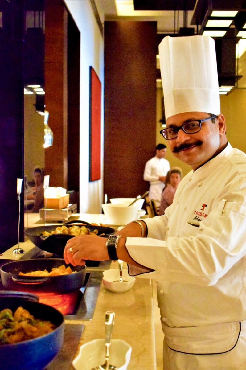 a chef standing in a kitchen preparing food at Trident Agra in Agra