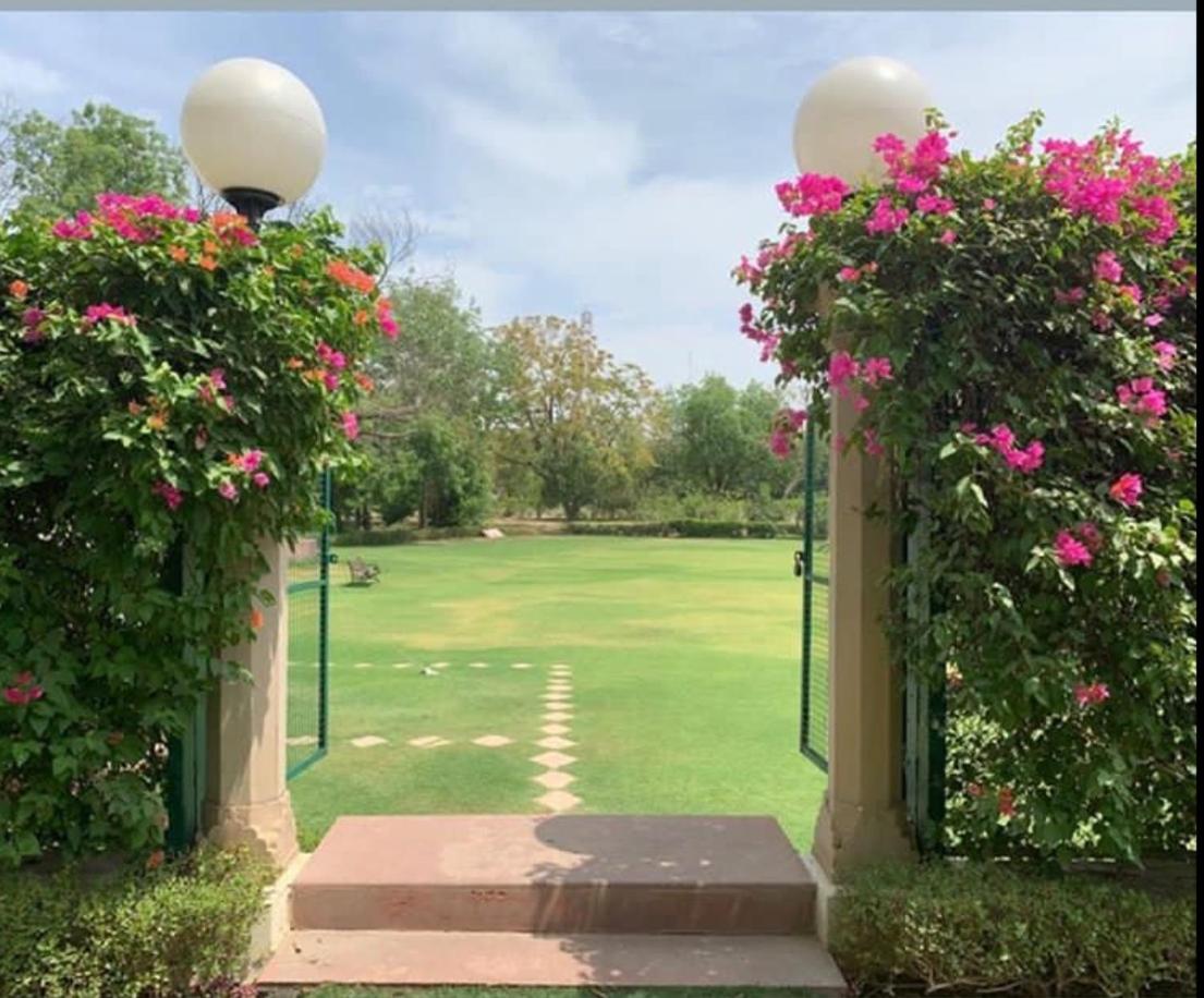 an entrance to a golf course with pink flowers at Trident Agra in Agra