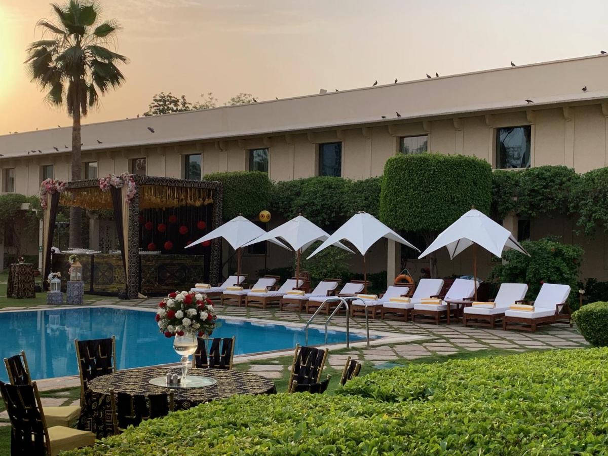 a hotel with a pool with chairs and a table with at Trident Agra in Agra
