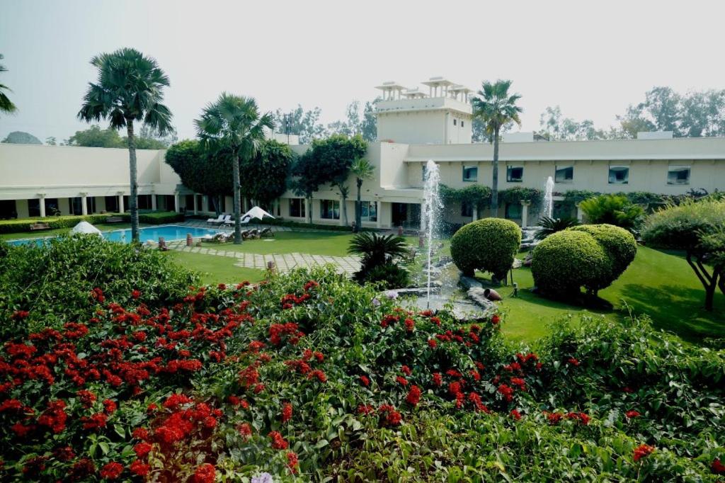 a building with a fountain in the middle of a garden at Trident Agra in Agra