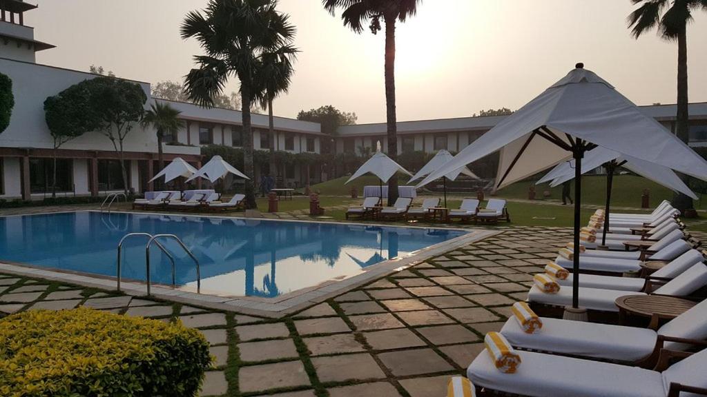 a swimming pool with lounge chairs and a hotel at Trident Agra in Agra