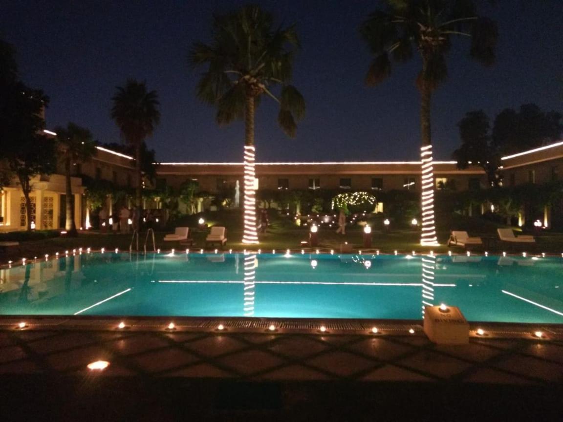a swimming pool at night with palm trees and a building at Trident Agra in Agra
