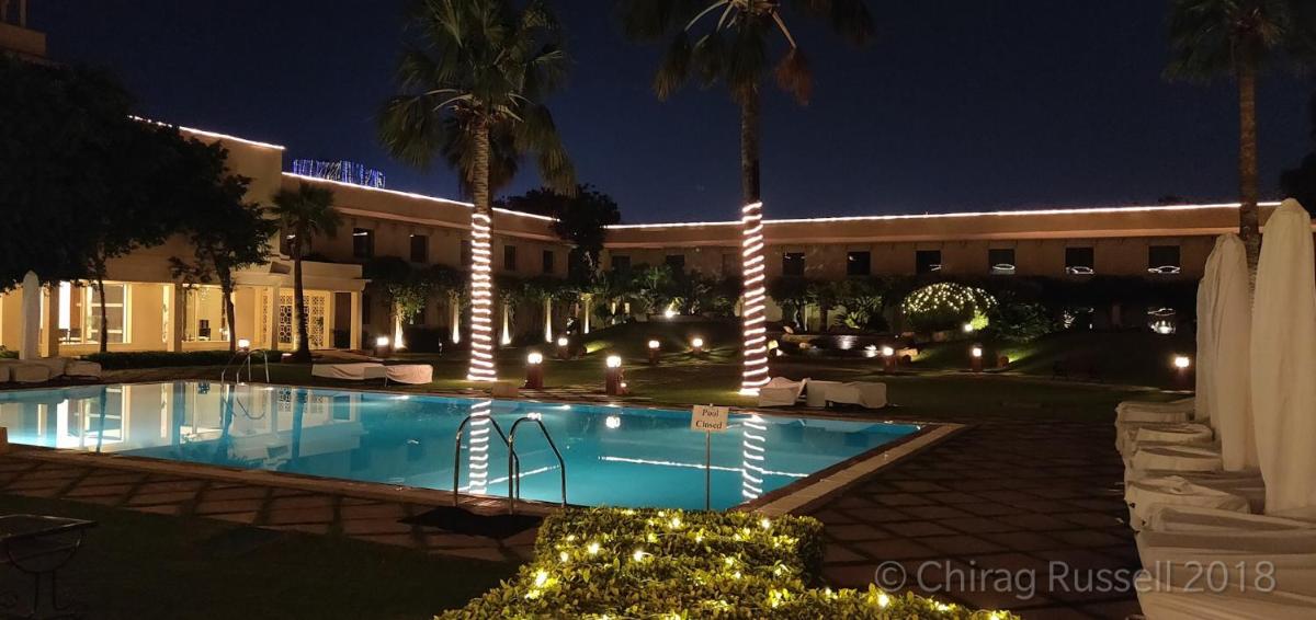 a hotel with a swimming pool at night at Trident Agra in Agra