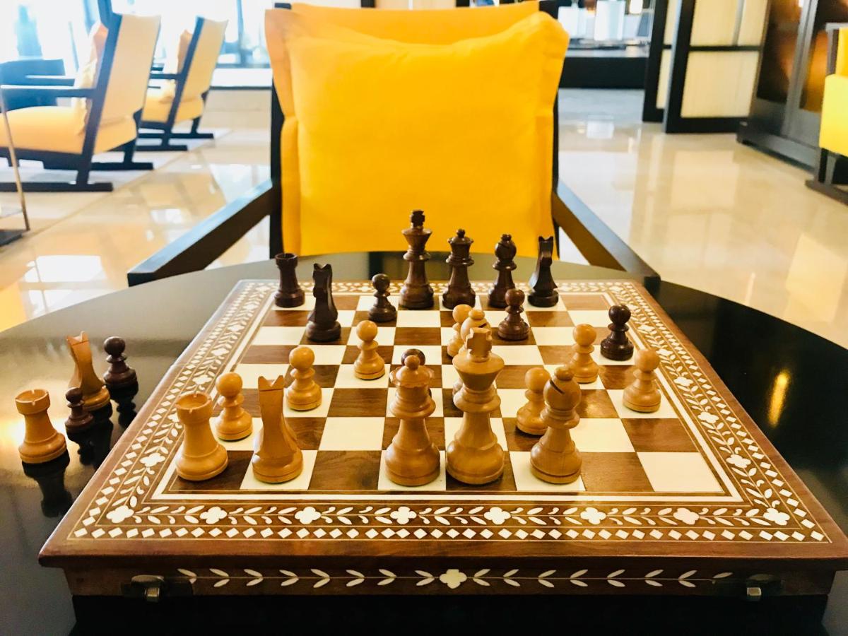 a chessboard on a table with a yellow chair at Trident Agra in Agra