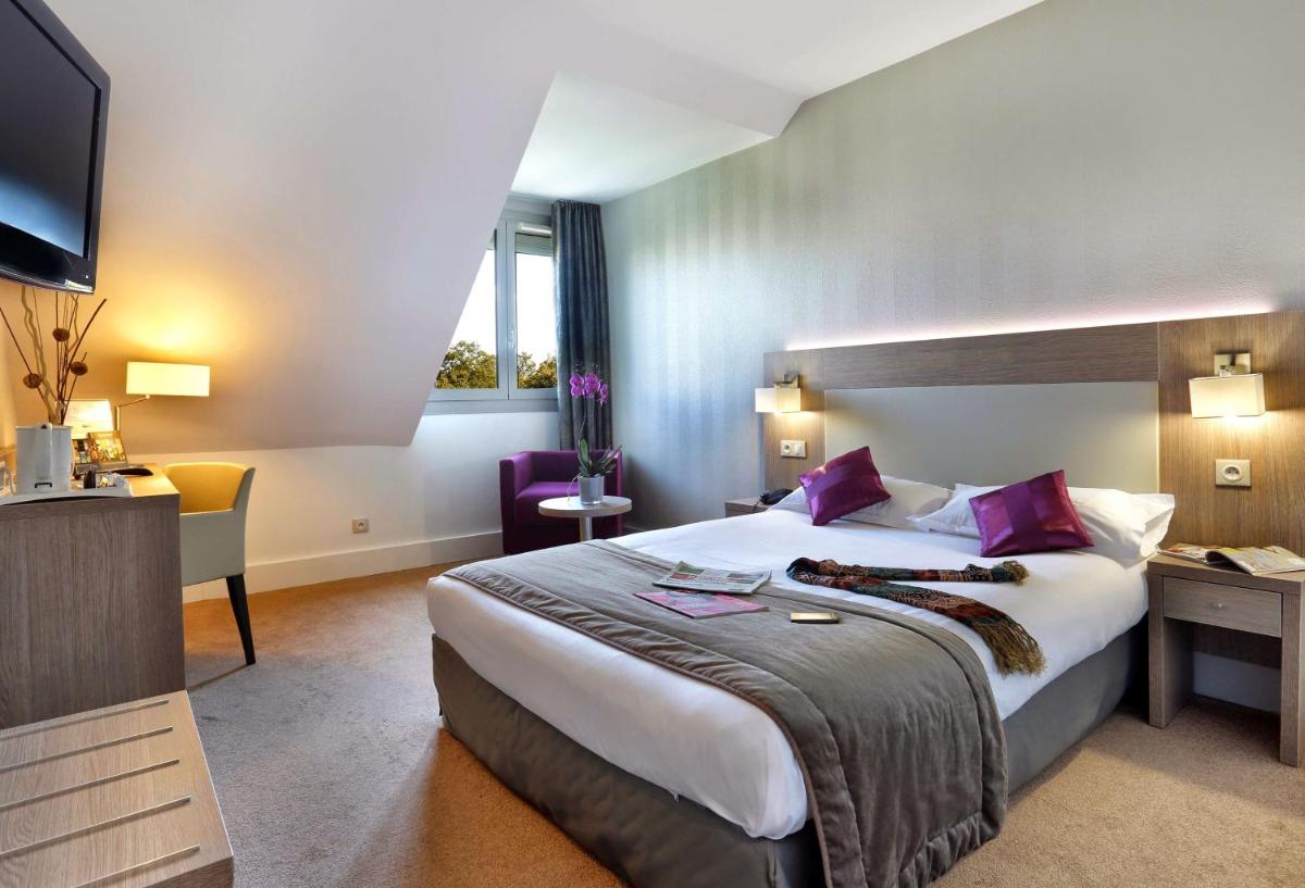 une chambre d'hôtel avec un grand lit et un bureau dans l'établissement Best Western Plus Hotel Du Parc Chantilly, à Chantilly