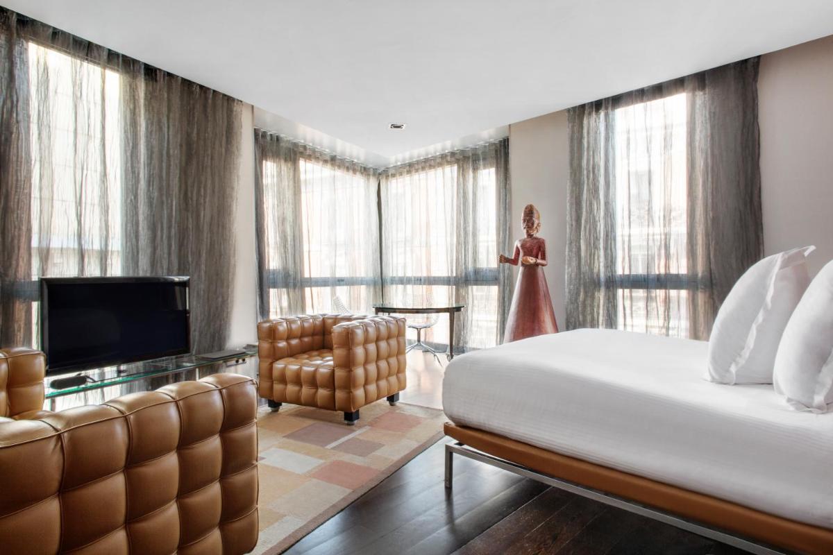 Un dormitorio con una cama, un televisor y una silla. en Hotel Urban, a Small Luxury Hotel of the World, en Madrid
