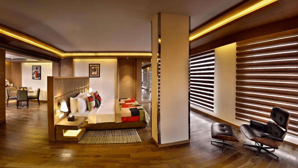 a bedroom with a bed and a desk and chairs at The Lalit Chandigarh in Chandīgarh
