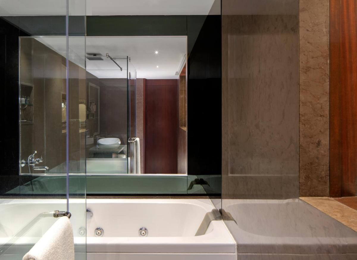 a bathroom with a tub and a sink with a mirror at Radisson Blu Atria Bengaluru in Bengaluru a bathroom with a tub and a sink with a mirror at Radisson Blu Atria Bengaluru in Bengaluru