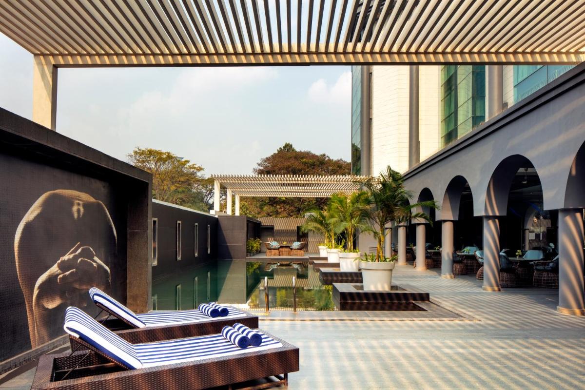 a resort with a swimming pool and lounge chairs at Radisson Blu Atria Bengaluru in Bengaluru a resort with a swimming pool and lounge chairs at Radisson Blu Atria Bengaluru in Bengaluru