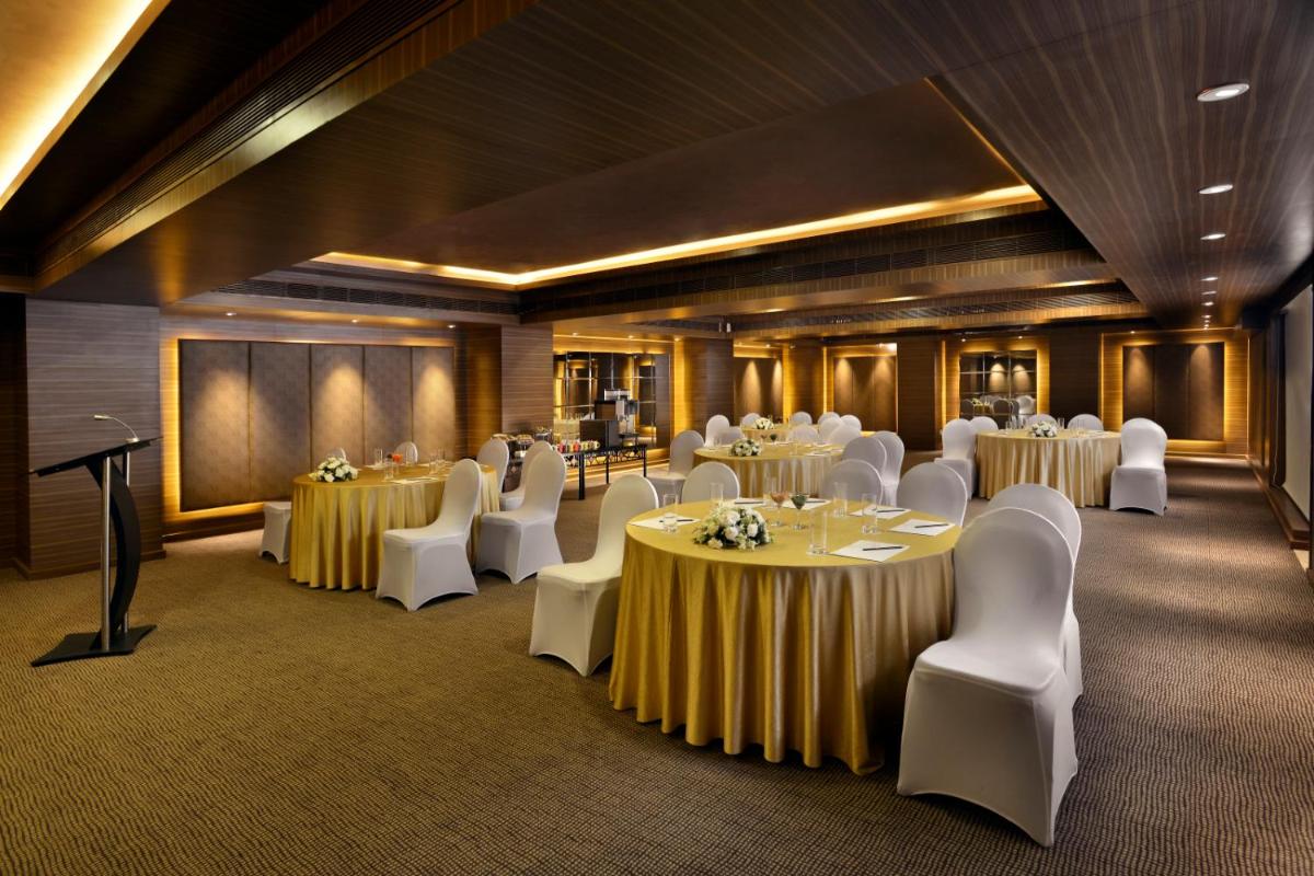 a banquet hall with tables and white chairs at The Lalit Chandigarh in Chandīgarh