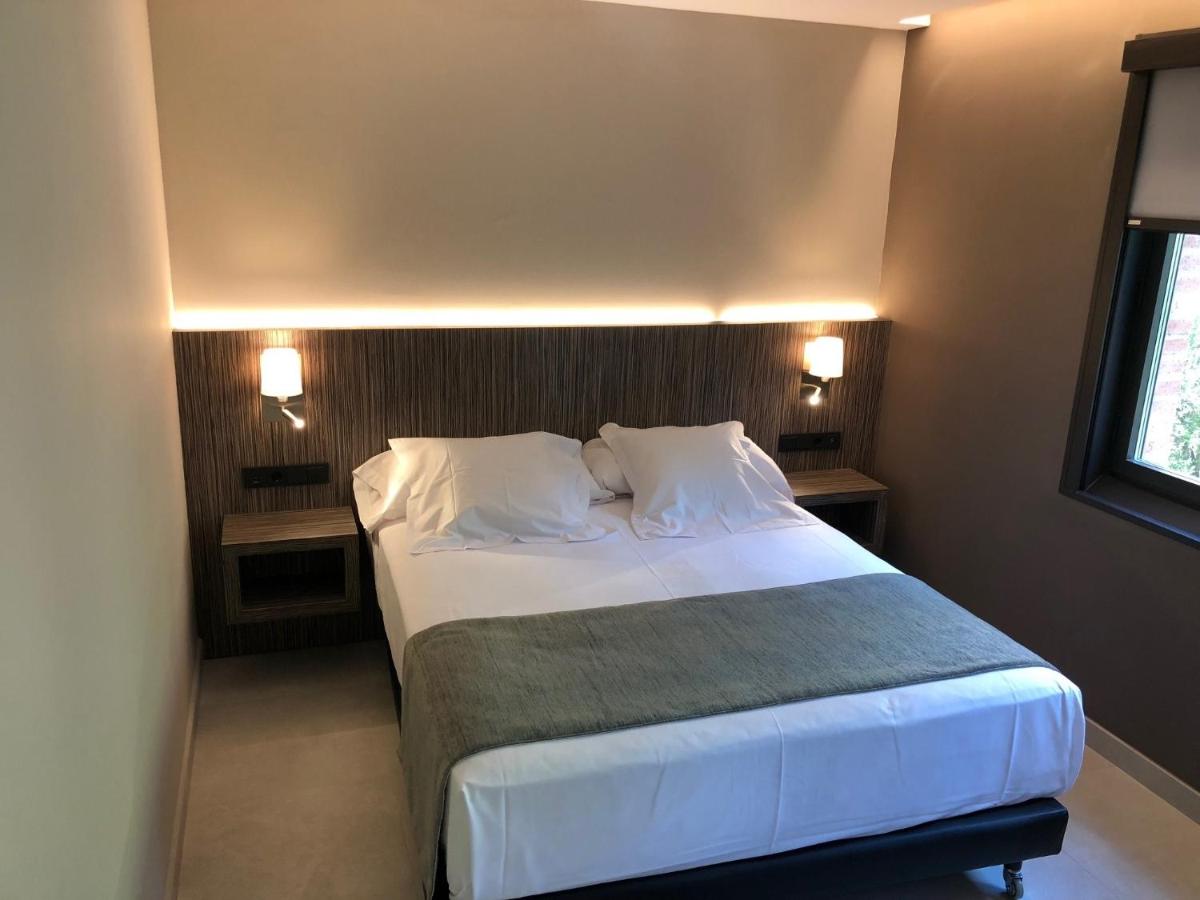 Un dormitorio con una cama con sábanas y almohadas blancas. en Hotel Balneario de La Virgen, en Jaraba