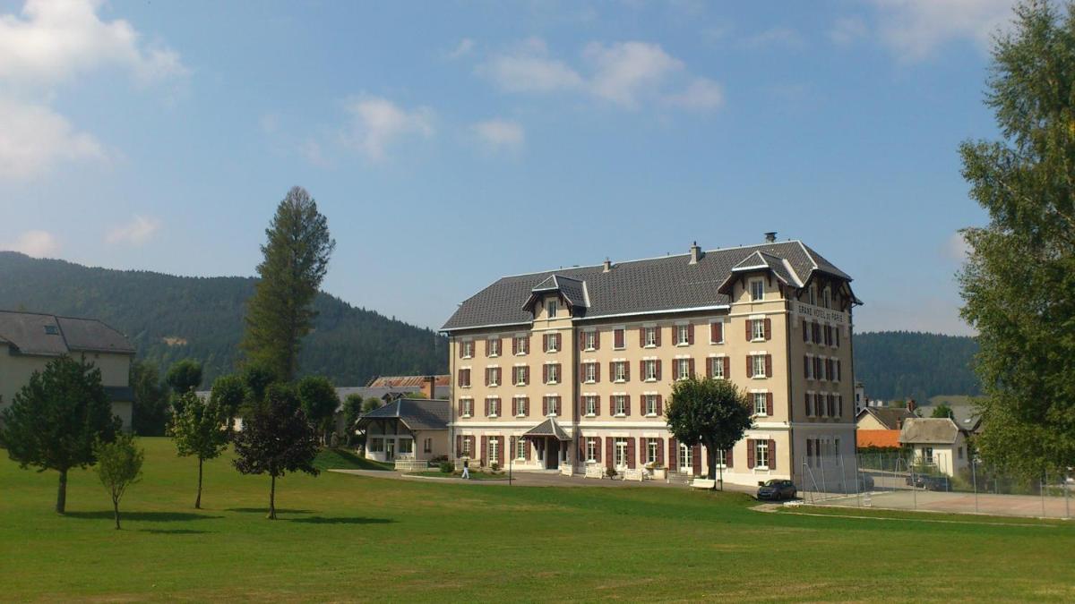 un grand bâtiment beige avec un toit noir sur un champ dans l'établissement Best Western Grand Hotel de Paris & Spa, à Villard-de-Lans