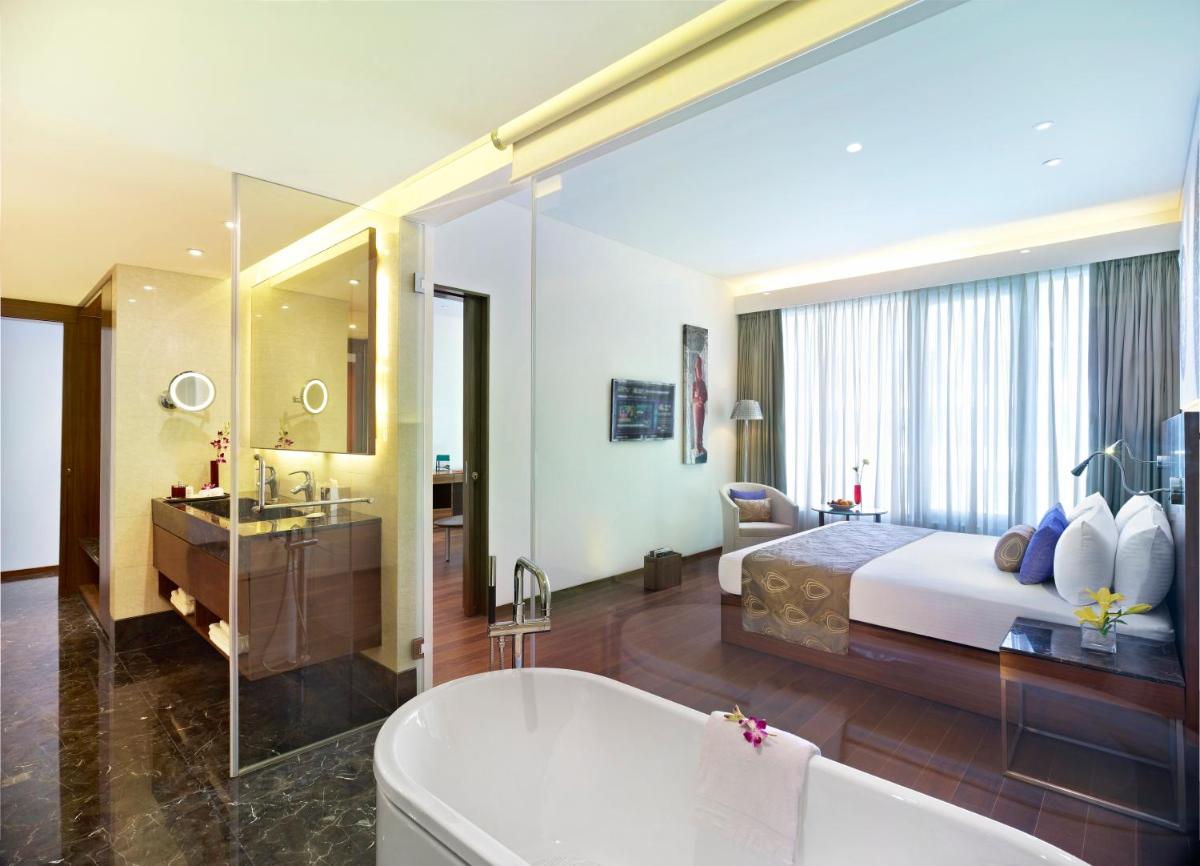 a bedroom with a bed and a tub and a bathroom at Vivanta Chennai IT Expressway OMR in Chennai