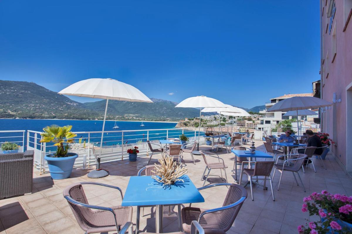 d'une terrasse avec des tables et des chaises offrant une vue sur l'eau. dans l'établissement Le Neptune & Spa, à Propriano