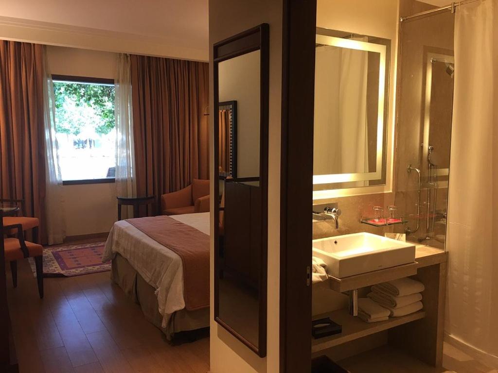 a bathroom with a bed and a sink and a mirror at Trident Agra in Agra