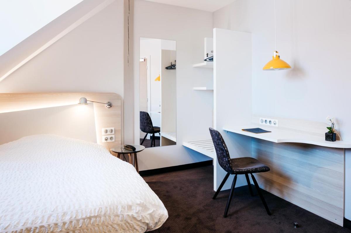 une chambre avec un lit, un bureau et des chaises dans l'établissement Logis Hôtel Restaurant Au Lion Rouge, à Bartenheim
