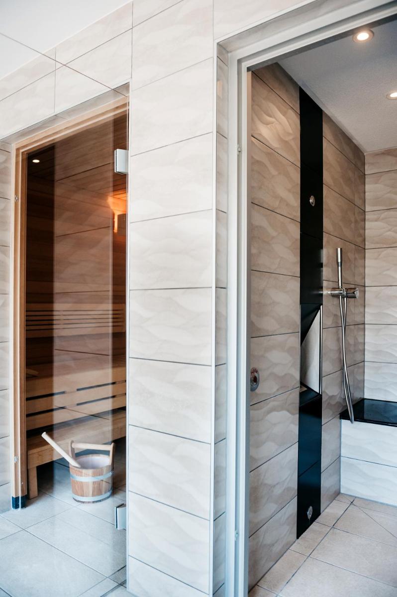 une salle de bains avec douche et porte vitrée dans l'établissement Logis Hôtel Restaurant Au Lion Rouge, à Bartenheim