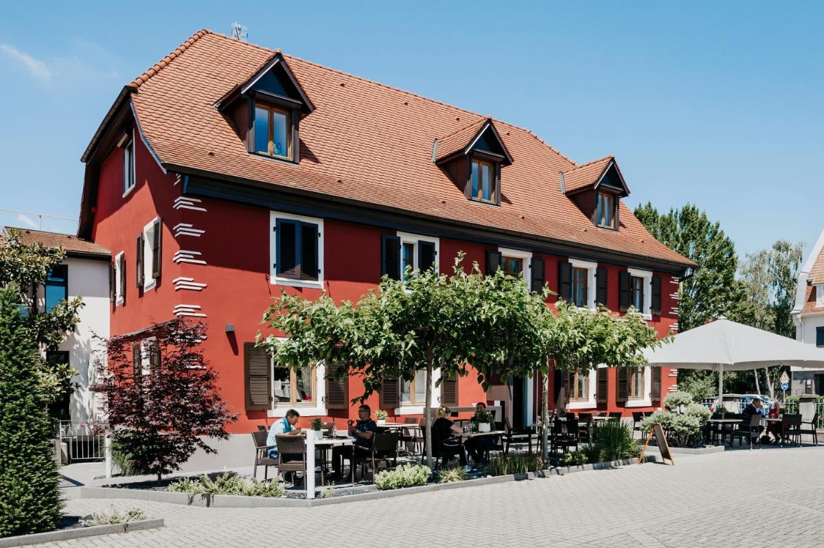 un bâtiment avec des tables et des chaises devant dans l'établissement Logis Hôtel Restaurant Au Lion Rouge, à Bartenheim