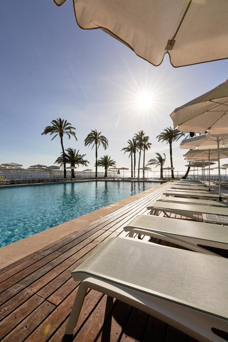 una piscina con sillas, palmeras y sol en Palace Bonanza Playa Resort & SPA by Olivia Hotels Collection, en Illetas