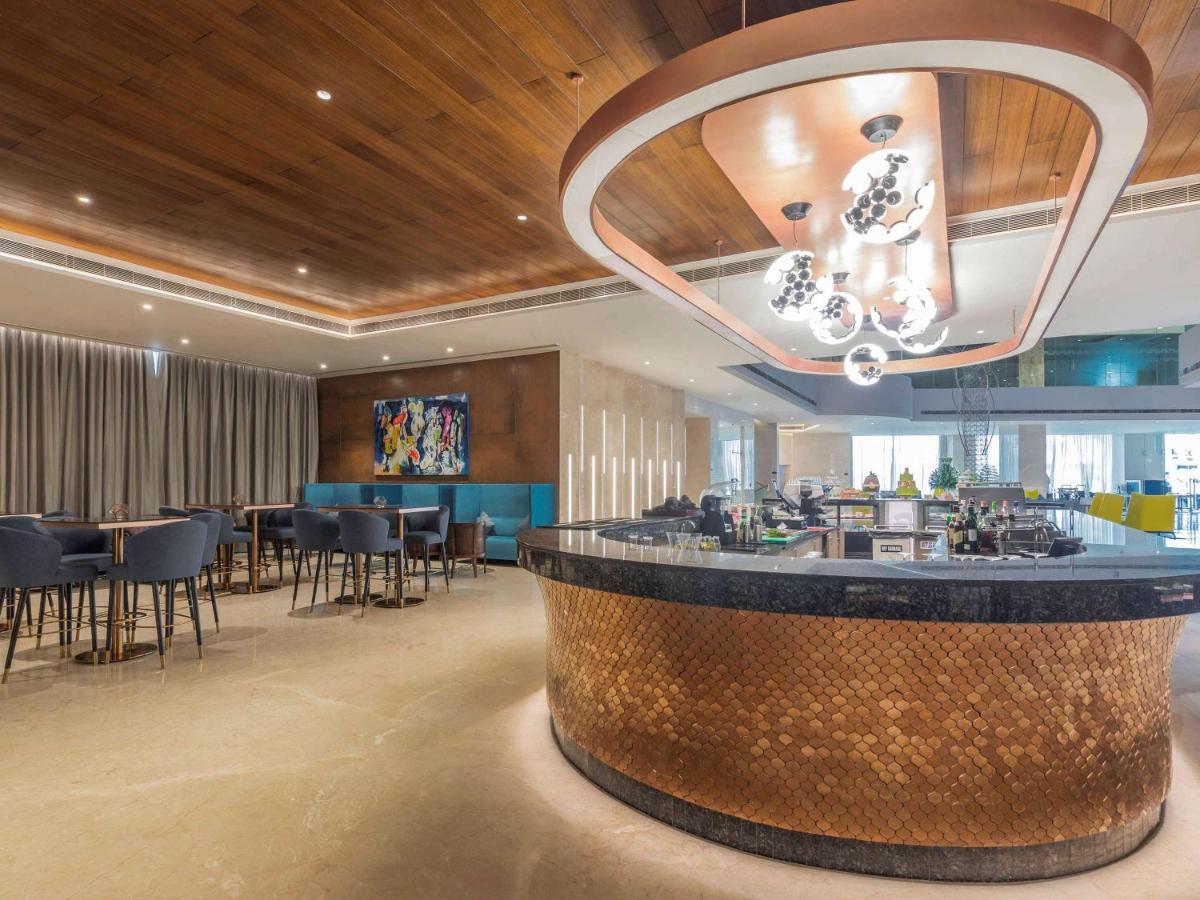 a lobby with a bar with chairs and tables at Novotel Vijayawada Varun in Vijayawāda