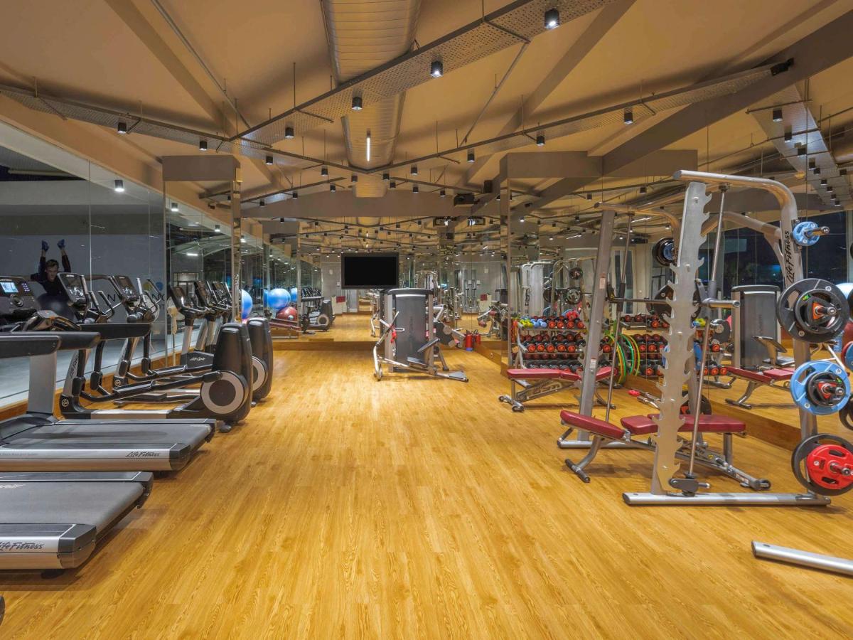a gym with a lot of treadmills and machines at Novotel Vijayawada Varun in Vijayawāda