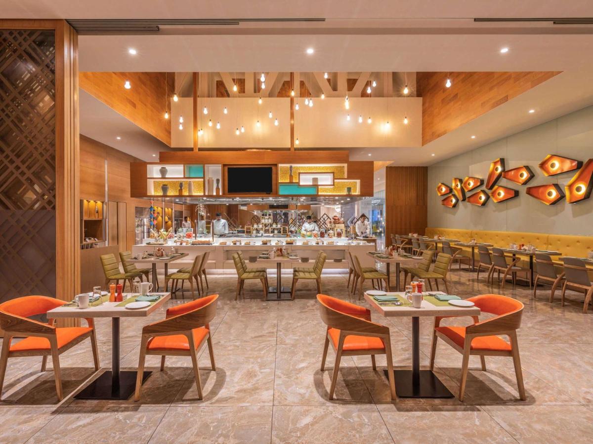 a restaurant with tables and chairs and a bar at Novotel Vijayawada Varun in Vijayawāda