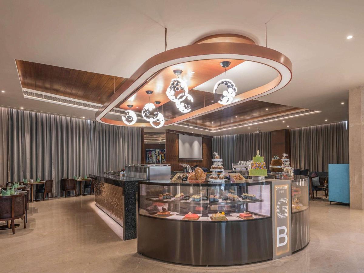 a restaurant with a counter with food on display at Novotel Vijayawada Varun in Vijayawāda