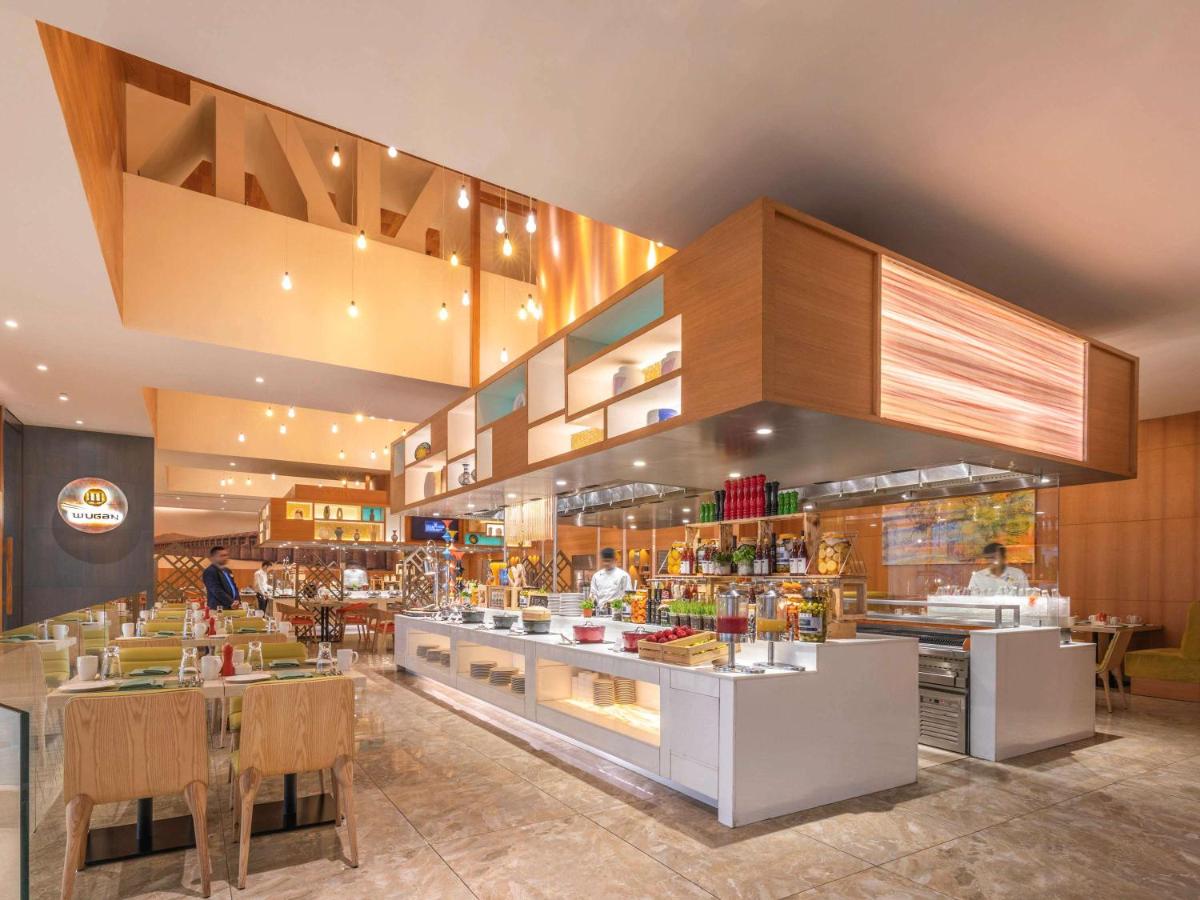 a restaurant with a bar with people in it at Novotel Vijayawada Varun in Vijayawāda