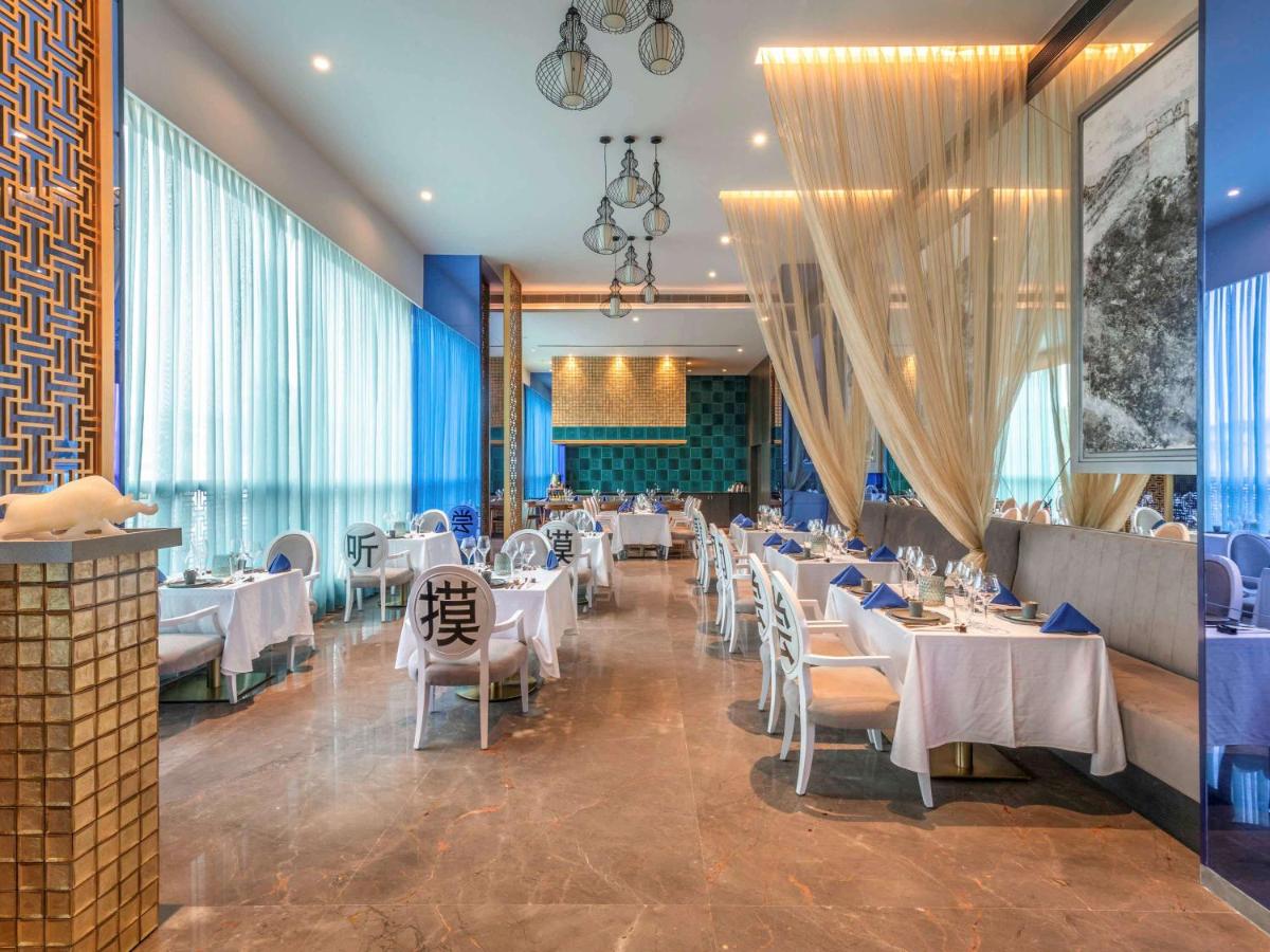 a dining room with white tables and chairs at Novotel Vijayawada Varun in Vijayawāda