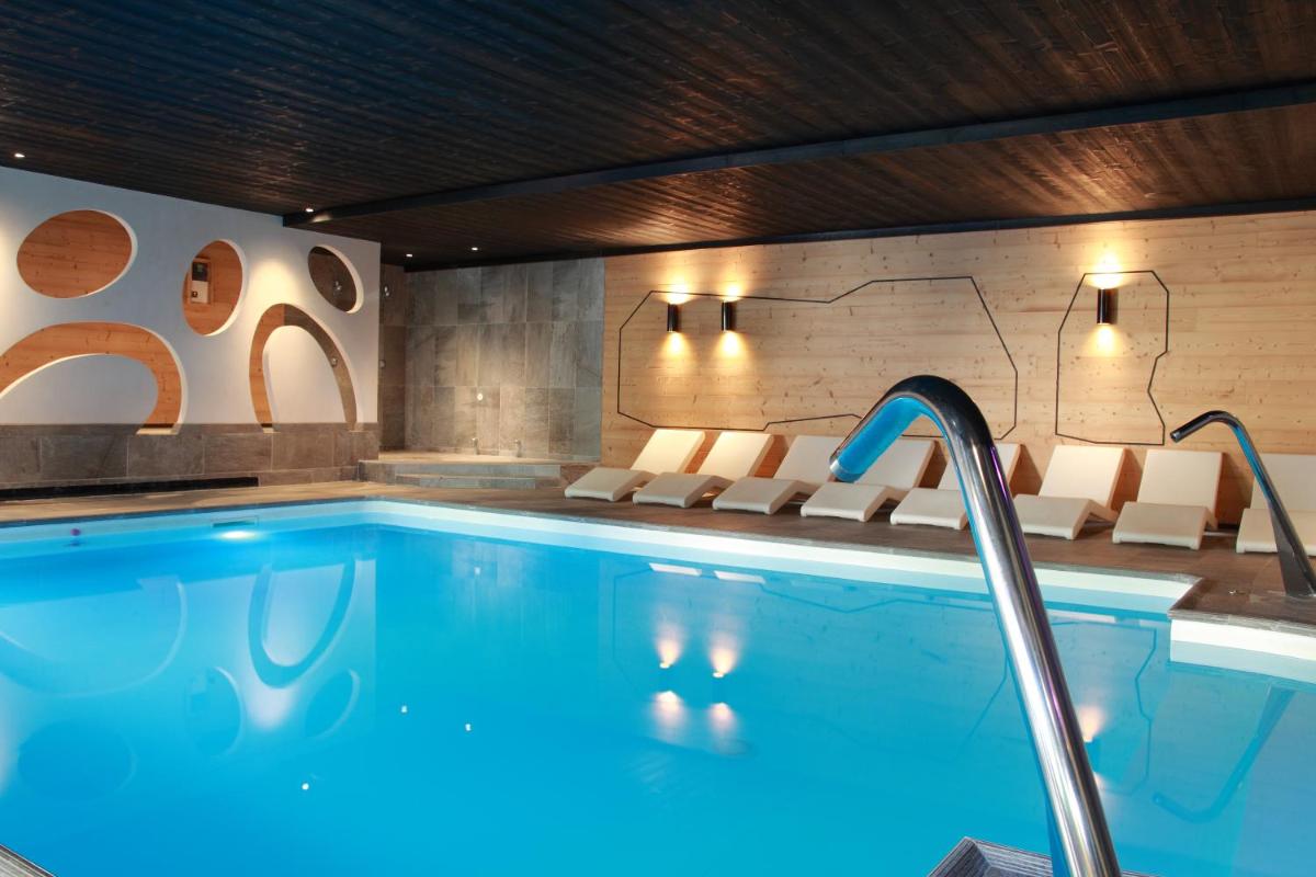 une piscine dans une chambre d'hôtel avec des chaises et une piscine dans l'établissement Hotel de la Jamagne & Spa, à Gérardmer