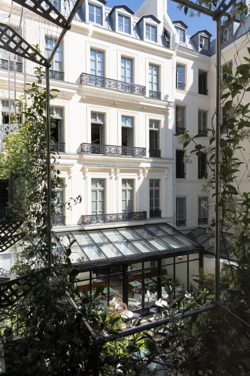 un grand bâtiment blanc avec un reflet de celui-ci dans l'établissement Les Jardins du Faubourg Hotel & Spa by Shiseido, à Paris