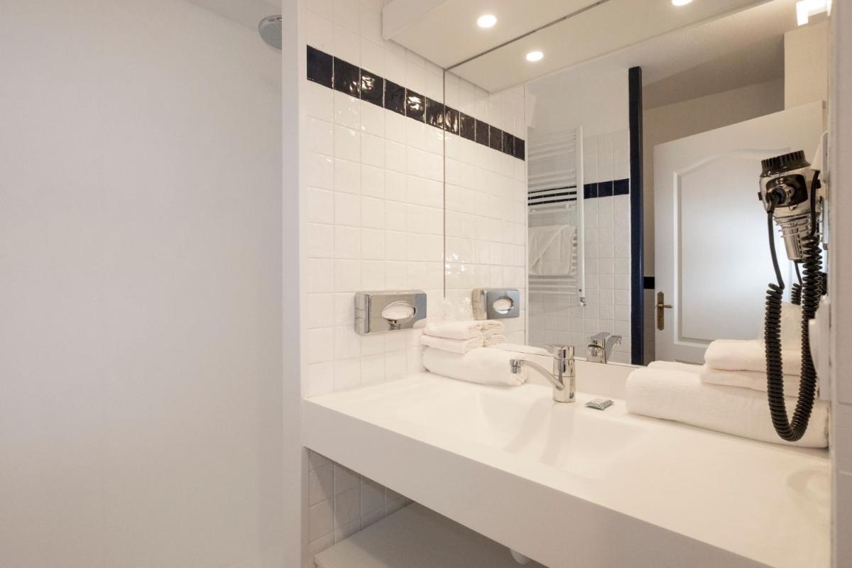 une salle de bain blanche avec un lavabo et un miroir dans l'établissement Thalacap Île de Ré - Thalasso & Spa, à Ars-en-Ré